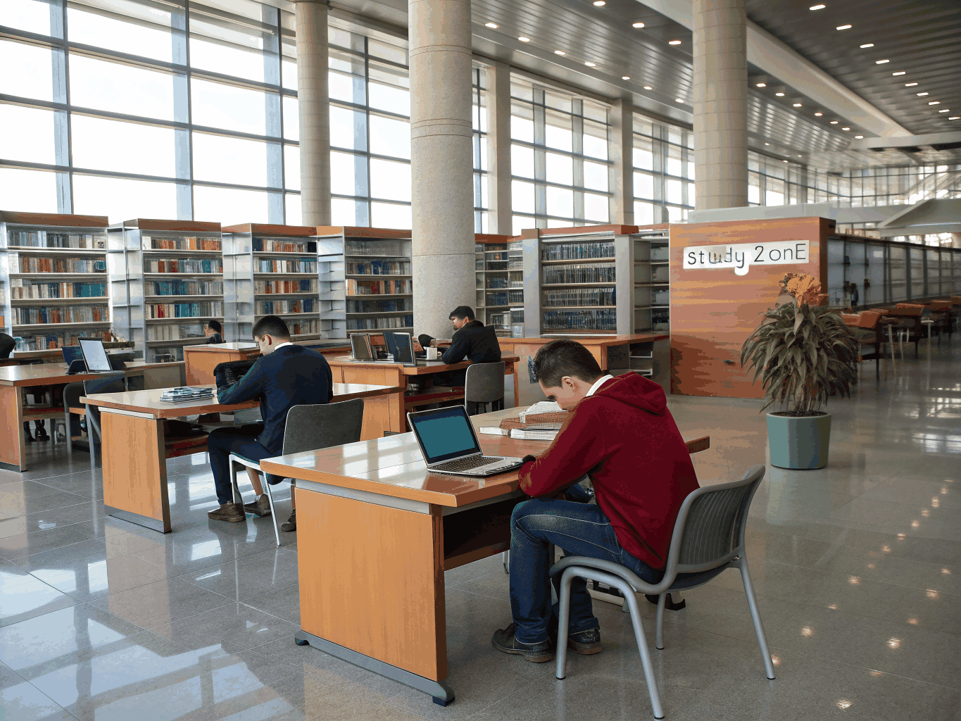 Group of students laughing around wooden library tables
