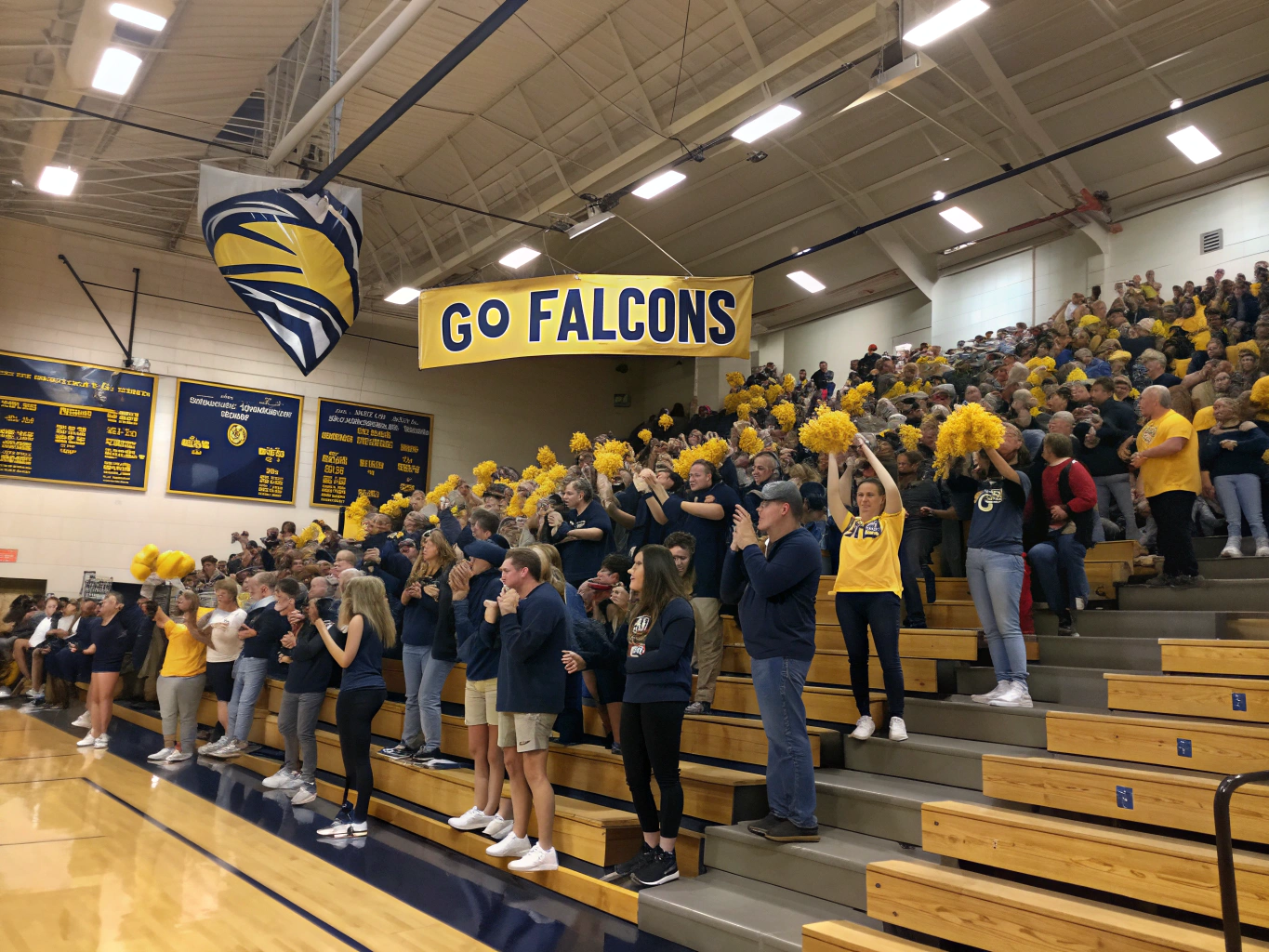 Enthusiastic high school student section cheering in the gymnasium bleachers
